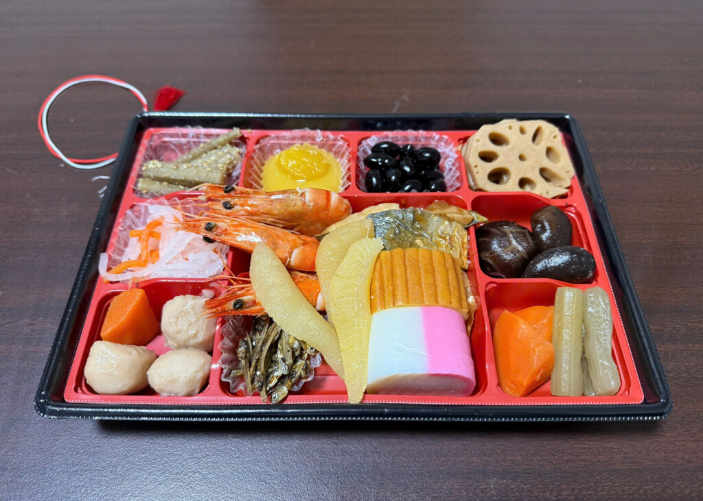Colorful osechi dishes including shrimp, black beans, lotus root, and sweet omelette
